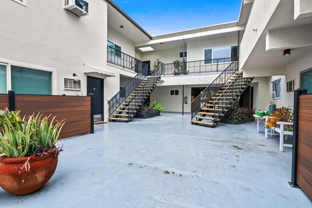 the courtyard of a building with stairs and a potted plant