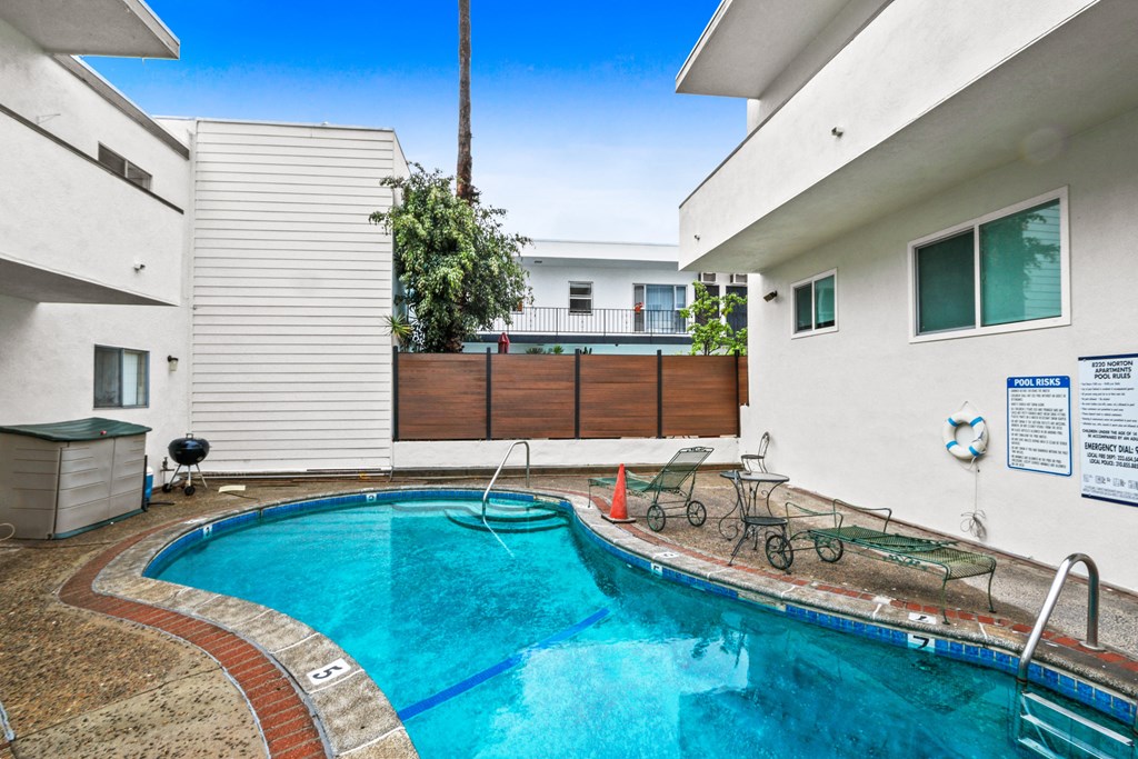 a swimming pool is next to a white house with a pool