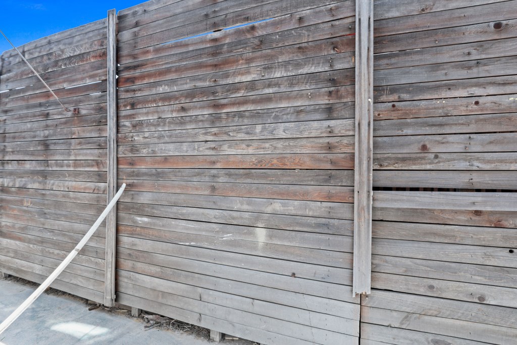 the side of a wooden fence with a metal gate
