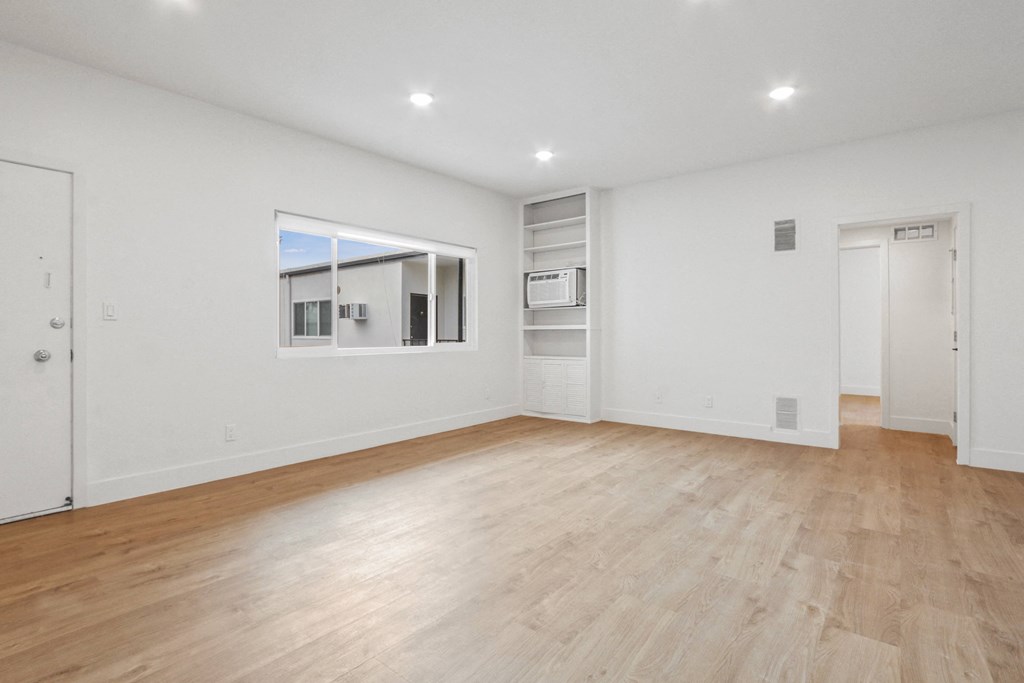 a living room with white walls and wooden floors and a window