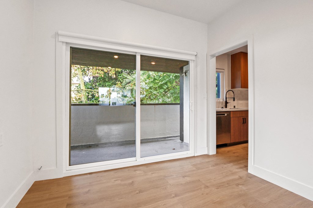 an empty living room with a sliding glass door to a balcony