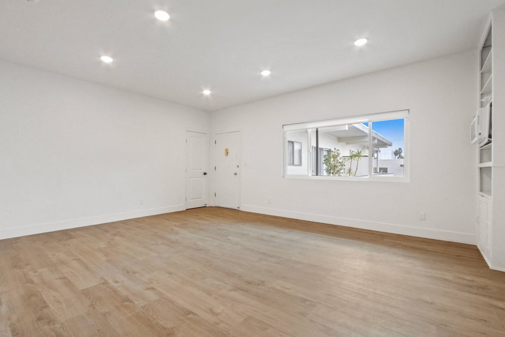 an empty living room with white walls and a window