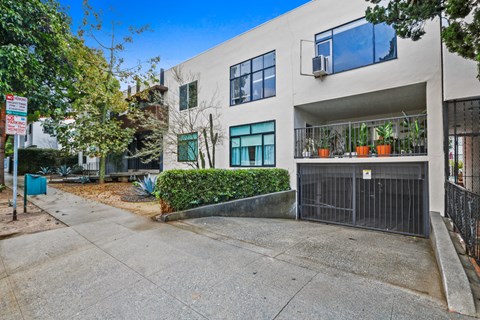 A modern building with a black gate and a green bush in front.