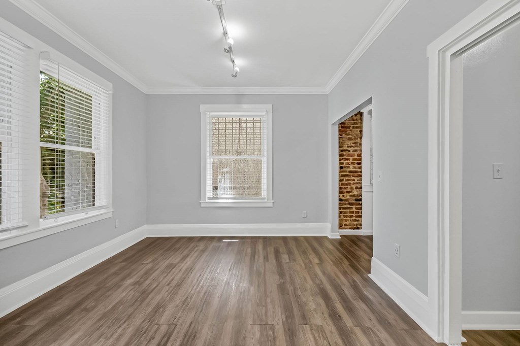 A room with wooden floors and a window with blinds.