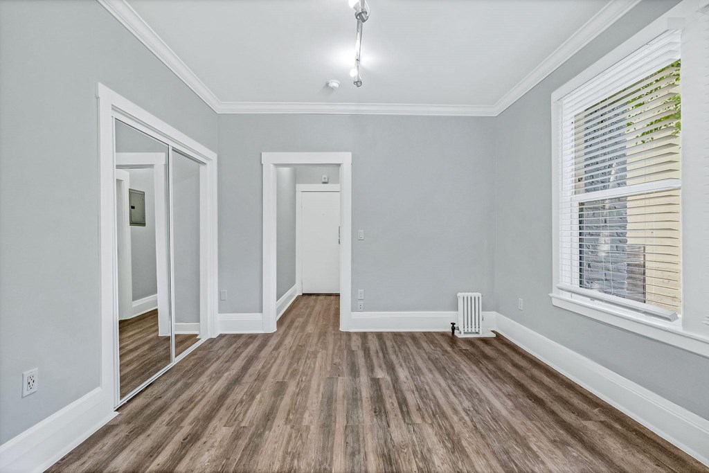 A room with wooden flooring and a window with blinds.