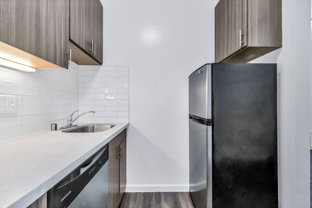 A modern kitchen with a black refrigerator and a white countertop.