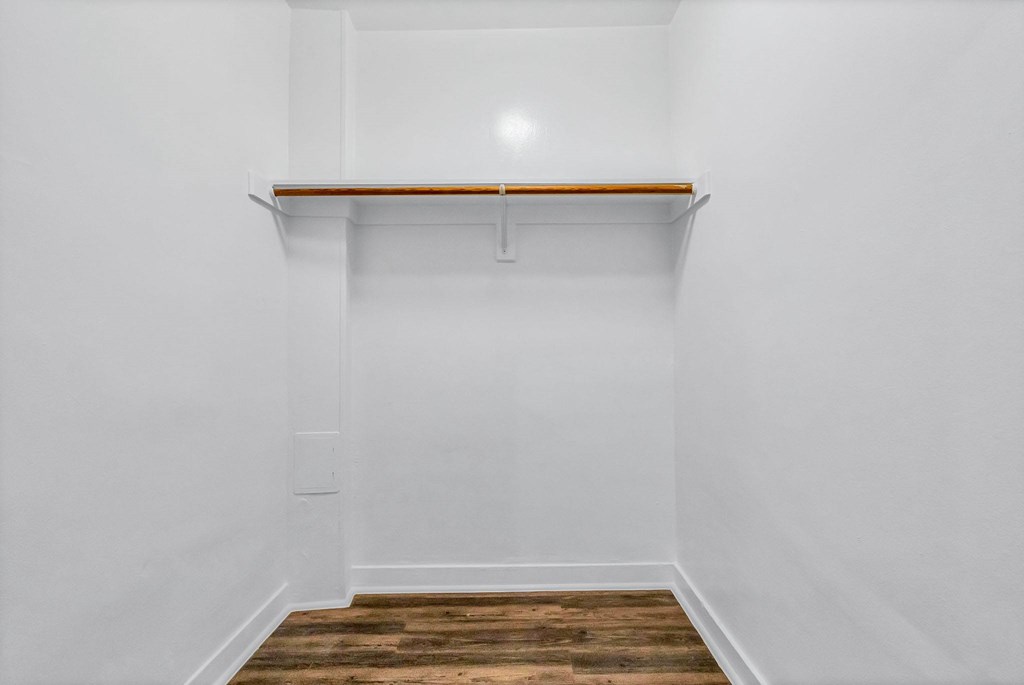 A white room with a wooden floor and a shelf.