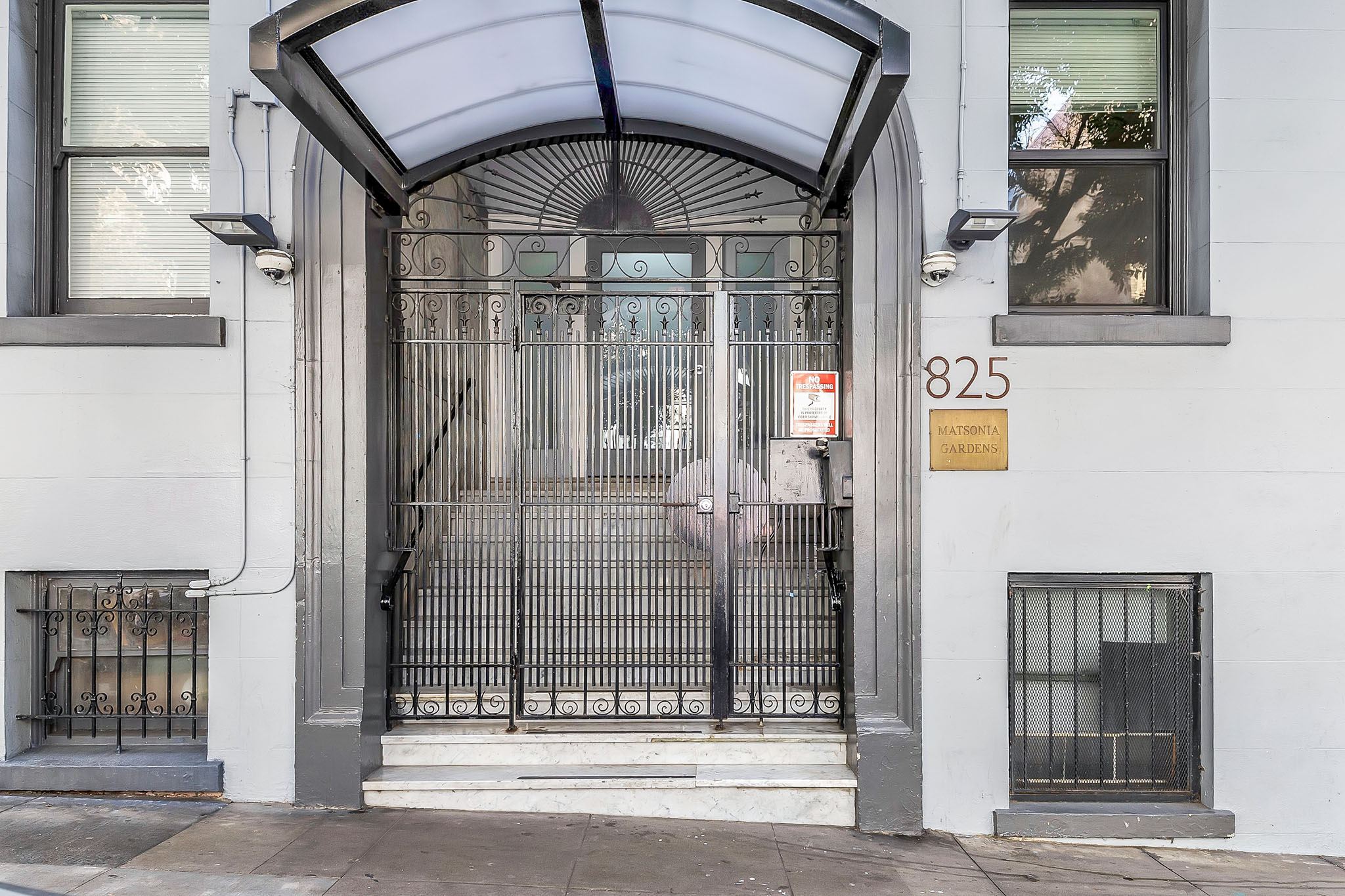 A white building with a black gate and a sign that says 825.
