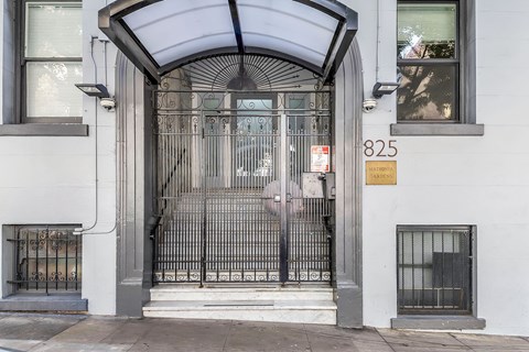 A white building with a black gate and a sign that says 825.