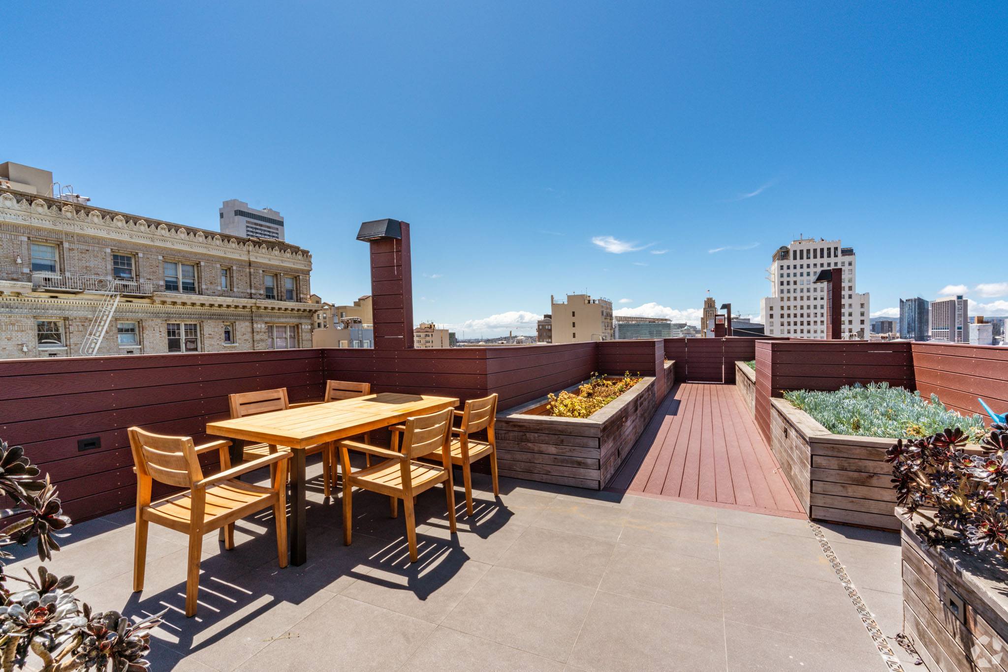 A wooden table and chairs are set up on a rooftop patio.