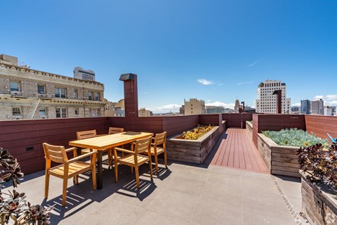 A wooden table and chairs are set up on a rooftop patio.