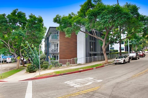 A street view with a car driving on the road and a building on the side.