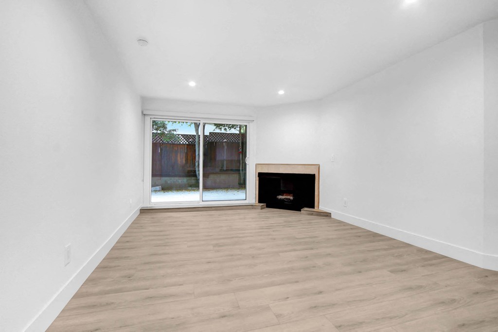 a living room with white walls and a window and wooden floors