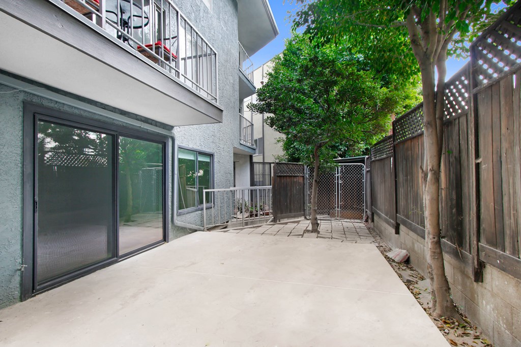 a patio with a fence and trees in front of a building