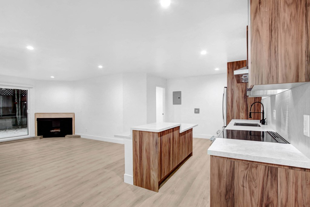 a living room with a fireplace and a kitchen with wooden cabinets