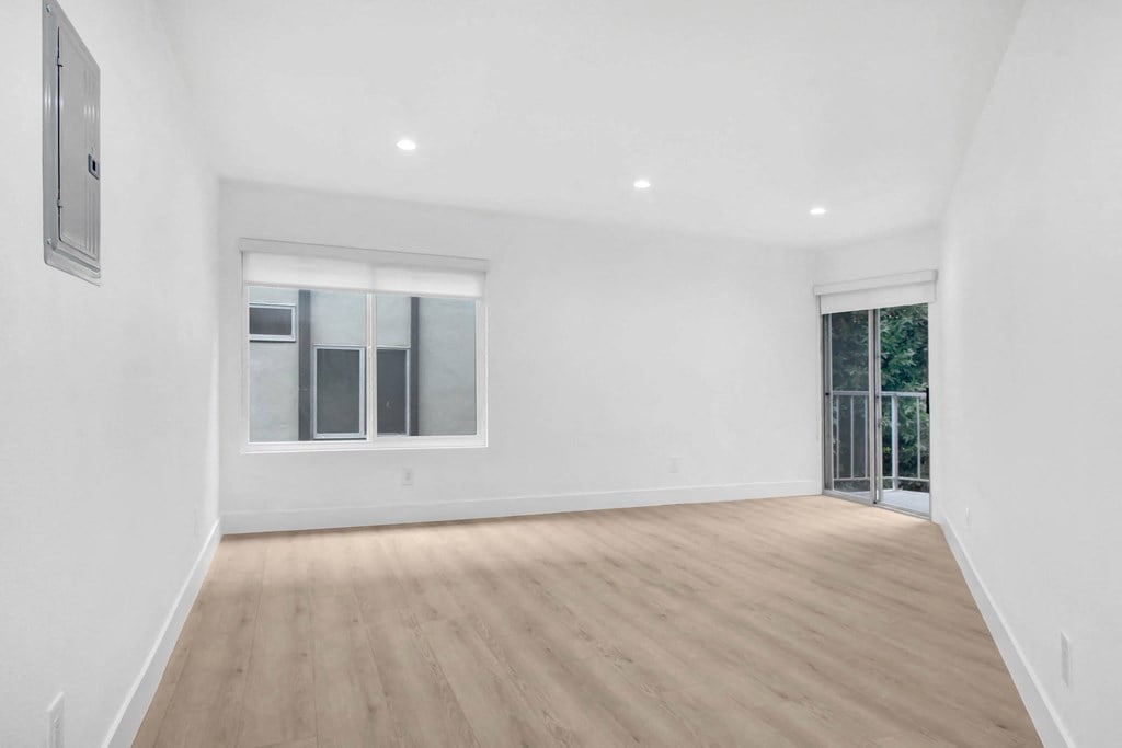 an empty living room with white walls and a sliding glass door