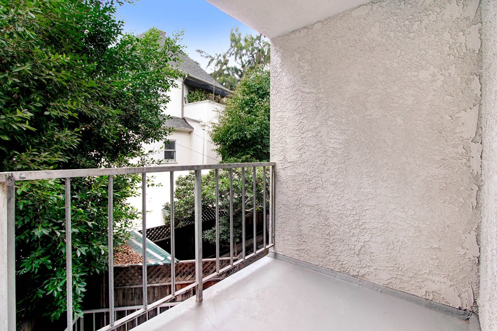 a balcony with a fence and a house in the background