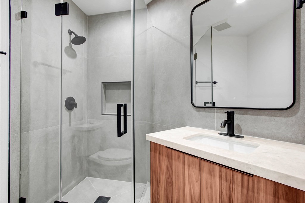 a bathroom with a sink and a shower and a mirror