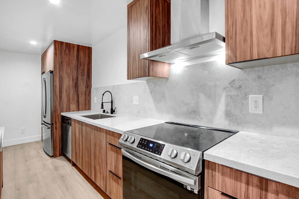 a kitchen with wooden cabinets and marble counter tops and a stainless steel stove