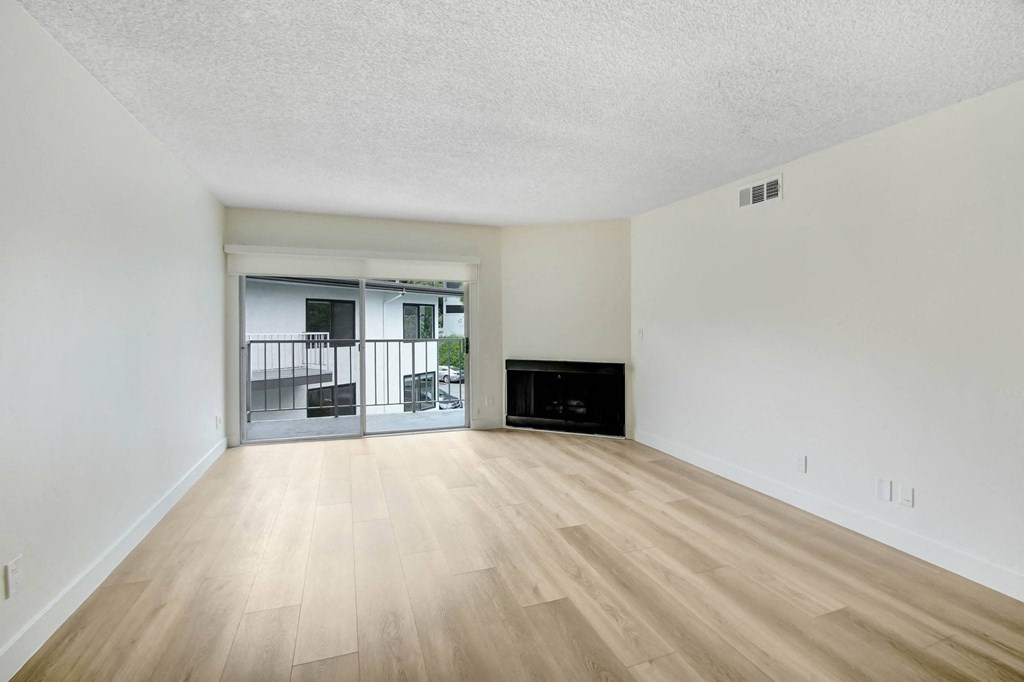 an empty living room with wood flooring and a fireplace