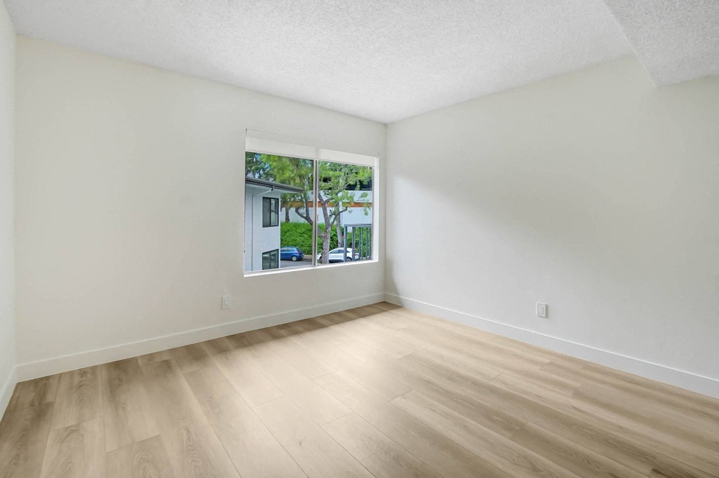 an empty living room with a large window and wooden floors