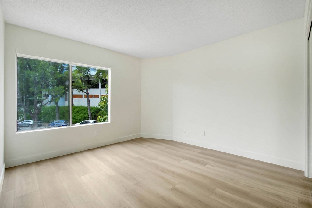 an empty living room with a large window and wooden floors
