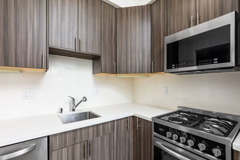 A modern kitchen with dark wood cabinets and stainless steel appliances.
