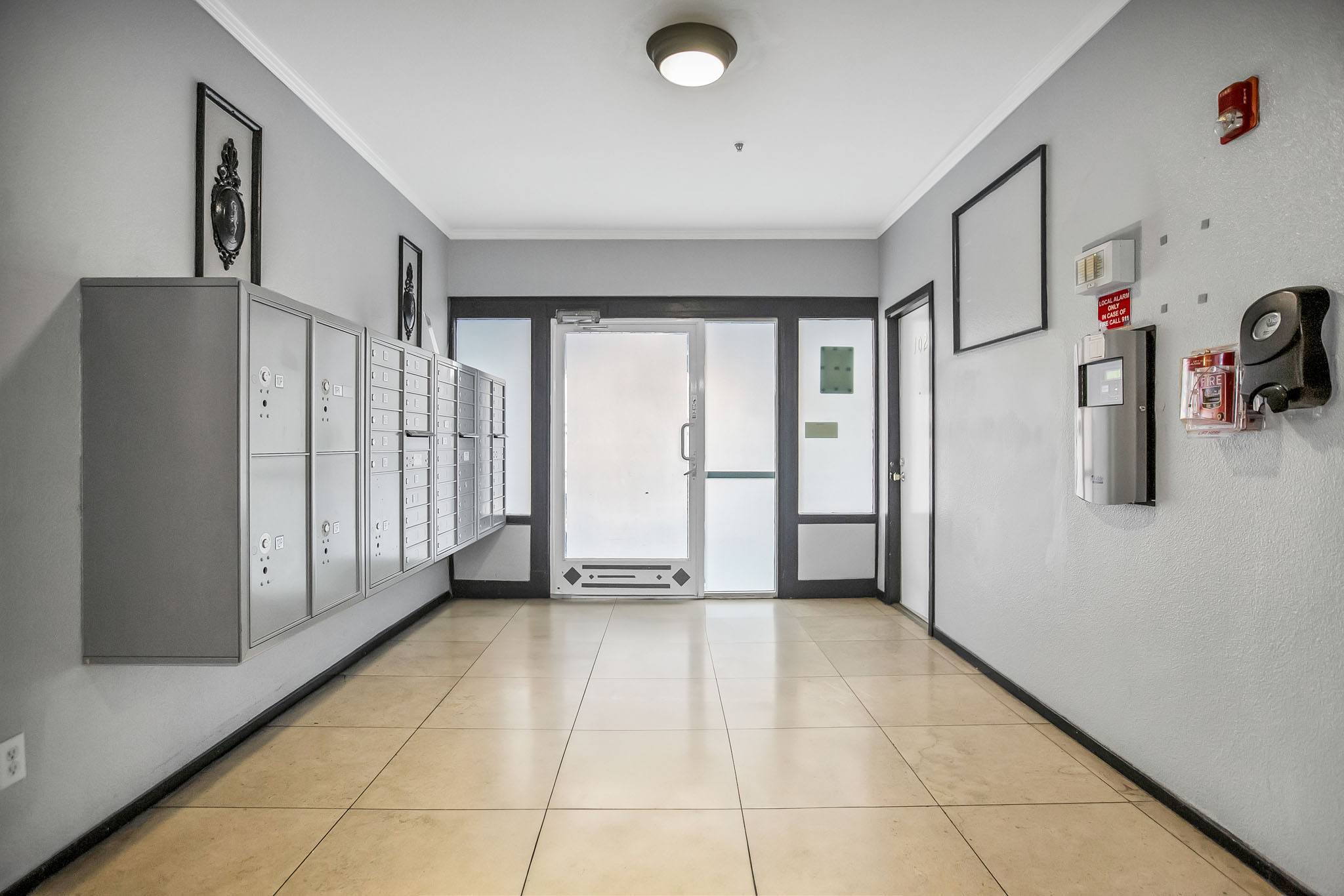 A hallway with a row of lockers on the left and a door at the end.