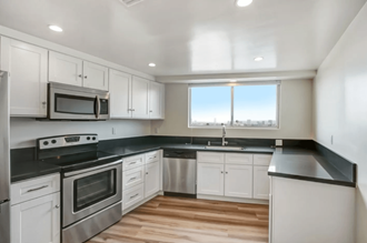 an empty kitchen with white cabinets and stainless steel appliances