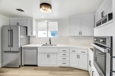 A modern kitchen with white cabinets and stainless steel appliances.