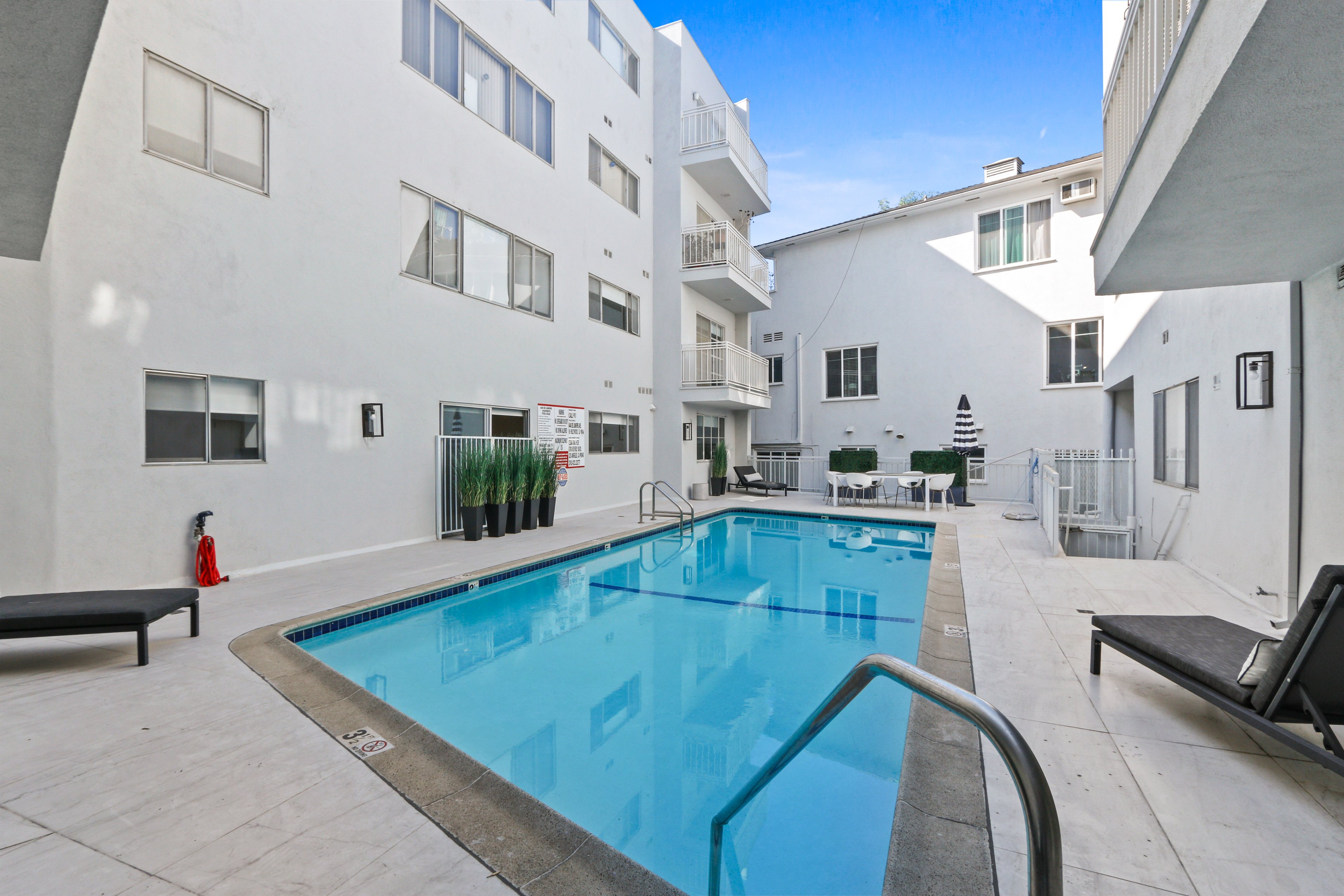 A swimming pool in a courtyard surrounded by white buildings.