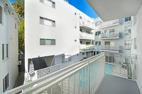 A white building with balconies and a pool.