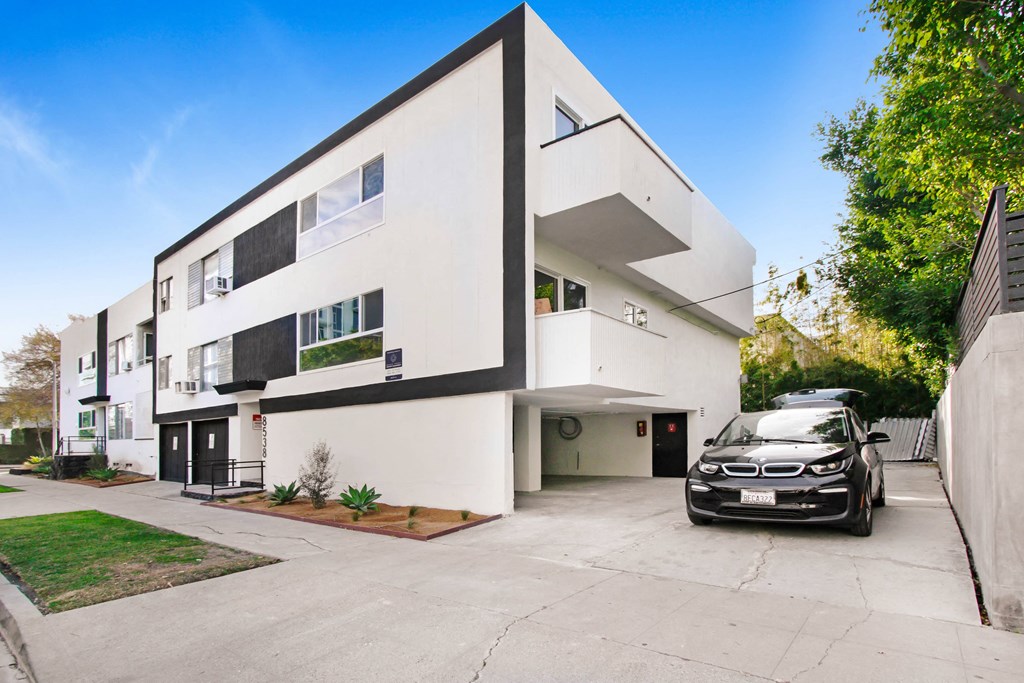 a white and black house with a car parked in front of it