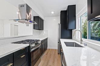 a kitchen with black cabinets and white countertops and a stainless steel refrigerator
