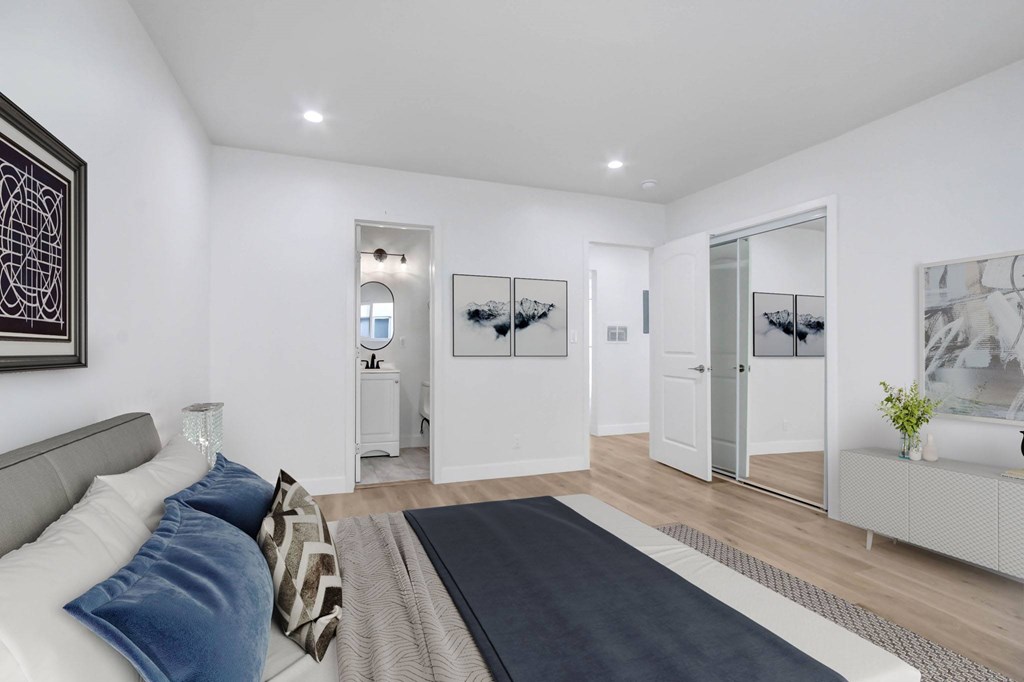 A modern bedroom with a large bed and a mirrored cabinet.