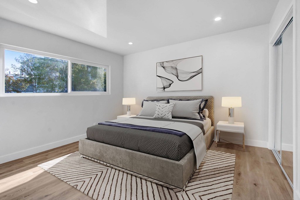 A bedroom with a large bed and a window overlooking trees.