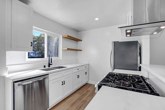 a kitchen with white cabinets and a stove and a sink