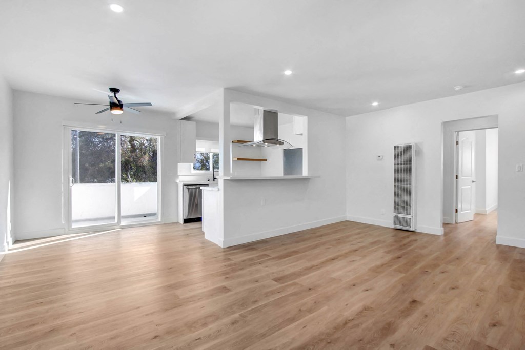 a living room with a hardwood floor and a door to a kitchen