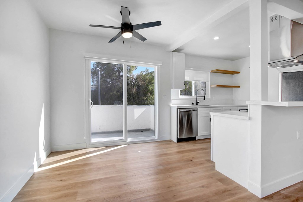 an empty living room with a sliding glass door to a kitchen