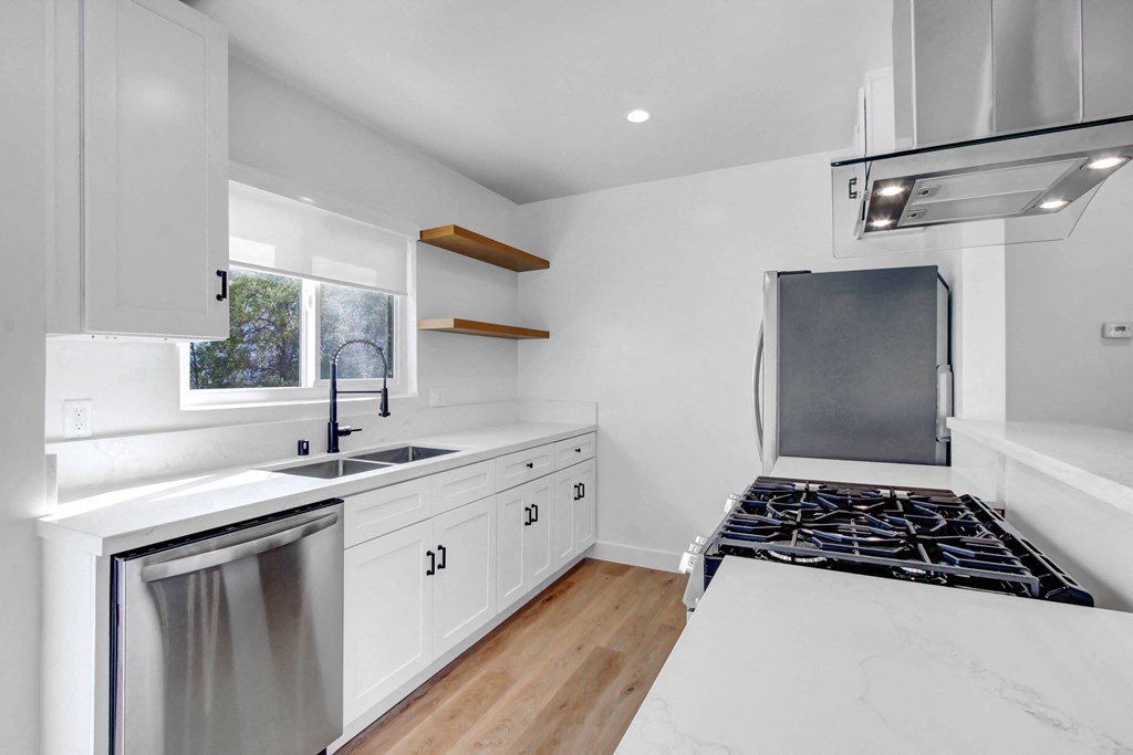a kitchen with white cabinets and a stove and a sink