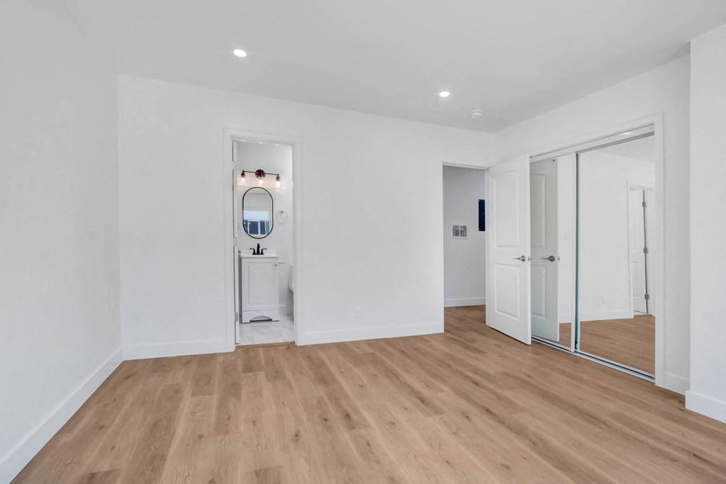 a living room with white walls and a mirror in the corner