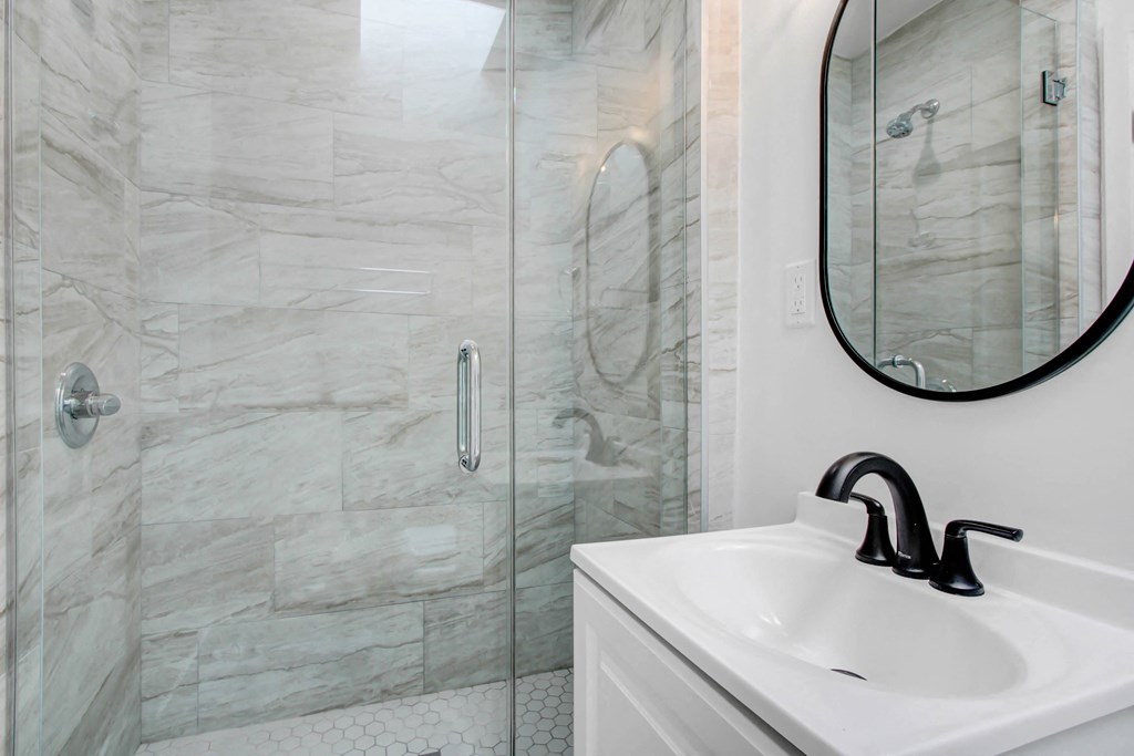 a white bathroom with a shower and a sink and a mirror