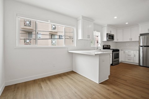A kitchen with white cabinets and a wooden floor.
