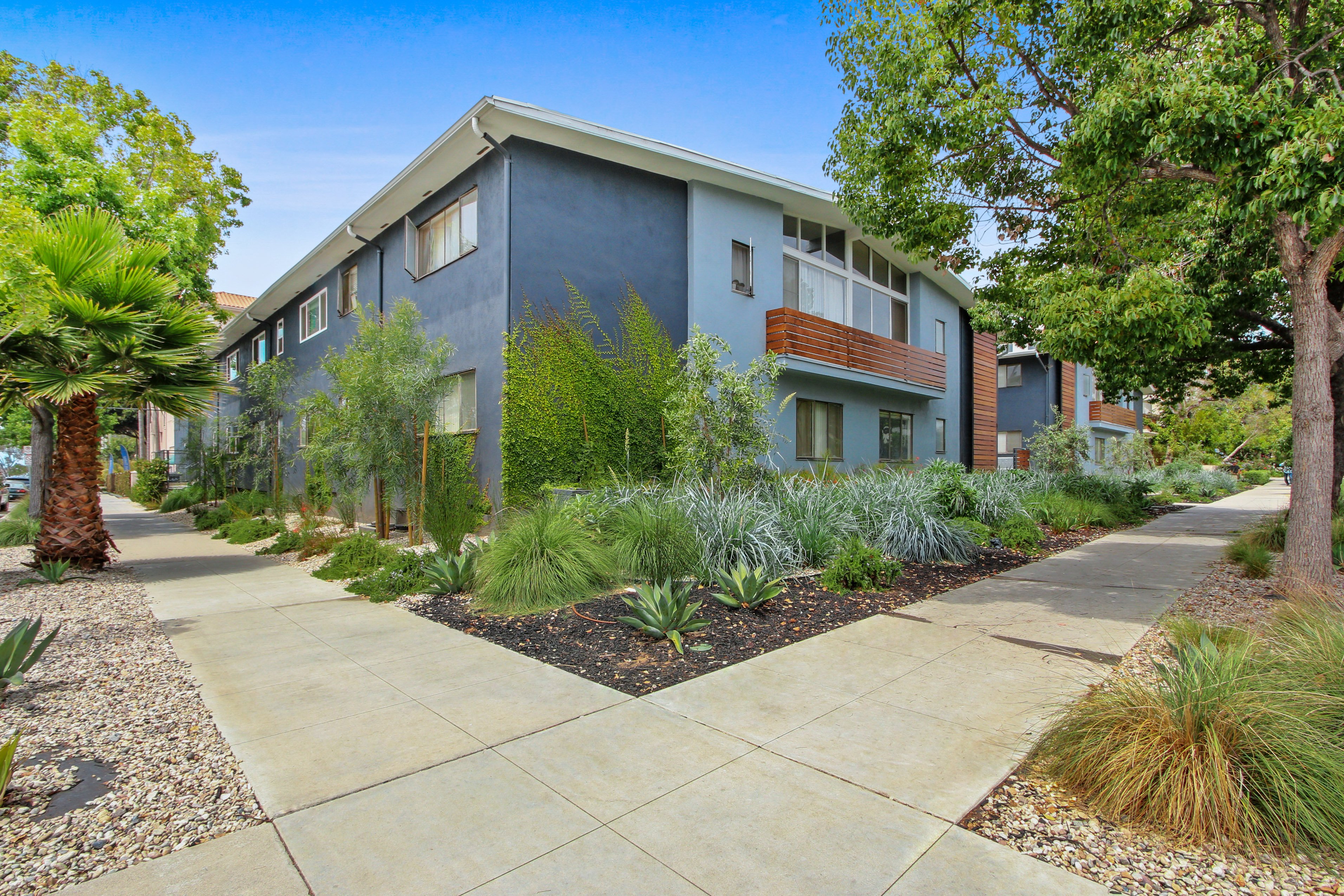 A modern apartment building with a well-maintained garden in front.