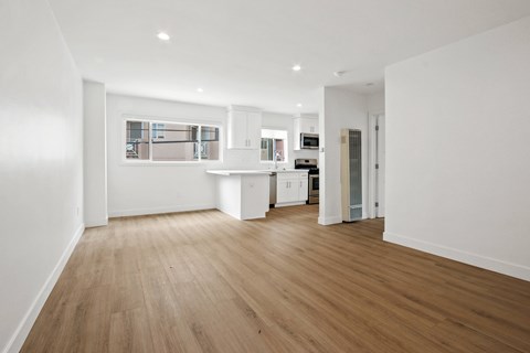 A spacious room with wooden flooring and white walls.