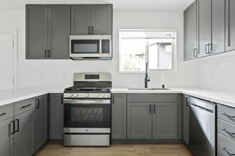 a kitchen with gray cabinets and a stove and a microwave