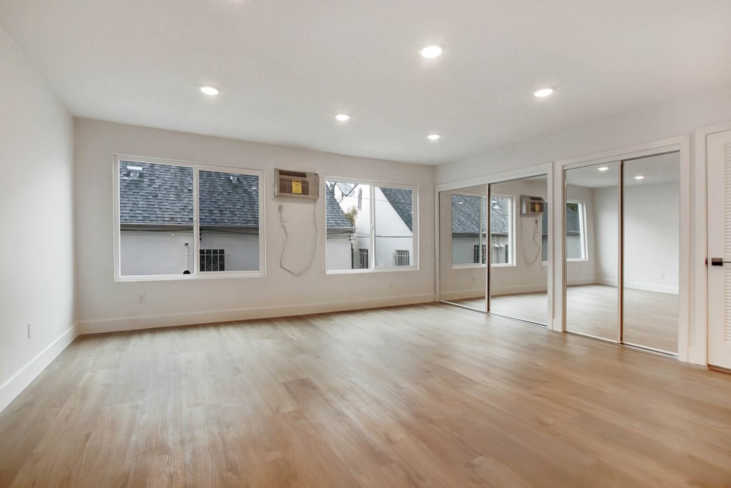 A spacious room with wooden floors and white walls.