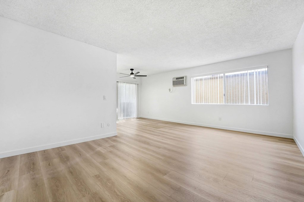A room with a ceiling fan and a window with blinds.