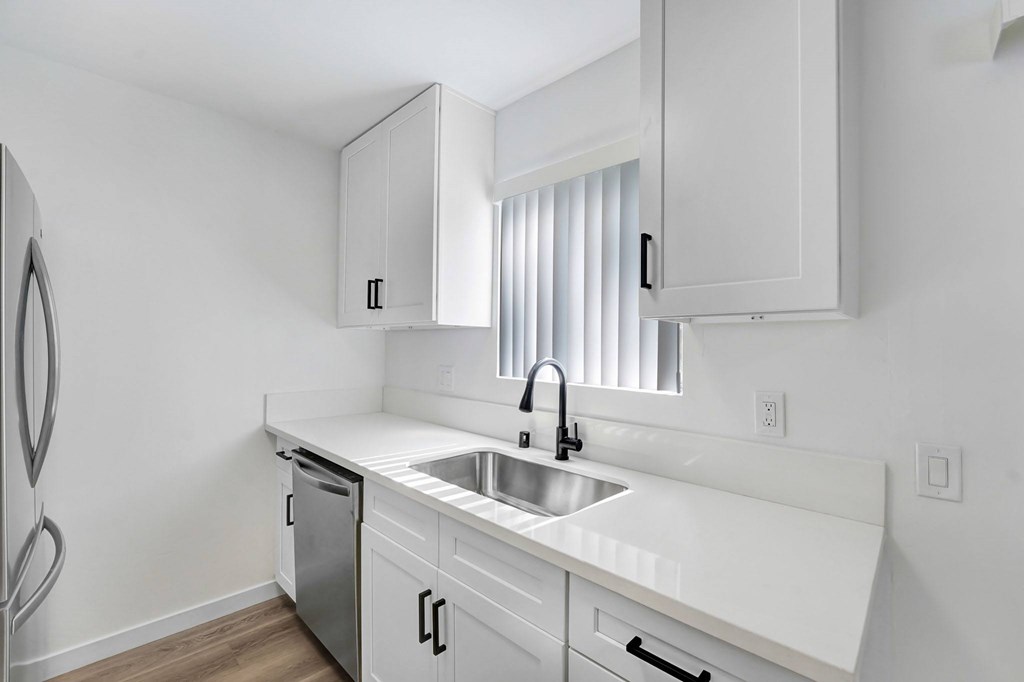 A white kitchen with a sink and a dishwasher.