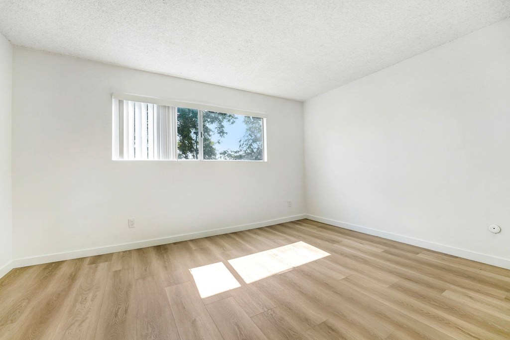 A room with wooden flooring and a window letting in natural light.